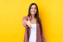 Young Brunette Woman Over Isolated Yellow Background Shaking Hands For Closing A Good Deal