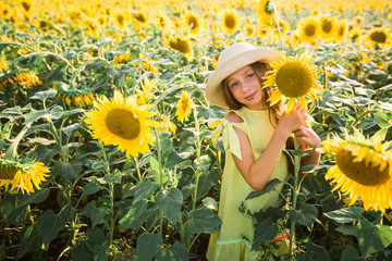 Wall Mural - beautiful young teenage girl in hat in a field of sunflowers in summer