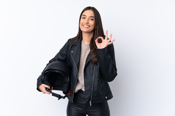 Wall Mural - Young brunette woman with a motorcycle helmet over isolated white background showing ok sign with fingers