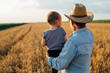 © cherryandbees - man holding his grandson standing in wheat field