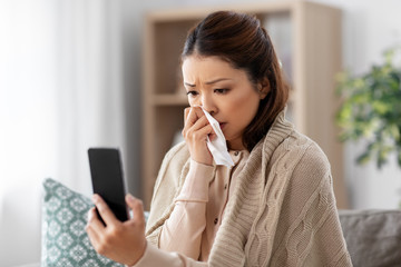 medicine, healthcare and technology concept - sick young asian woman with smartphone having video call or online consultation at home