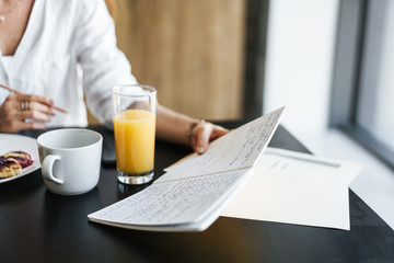 Cropped image of businesswoman having breakfast while working with laptop