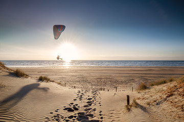 Wall Mural - man paragliding on beach at sunset