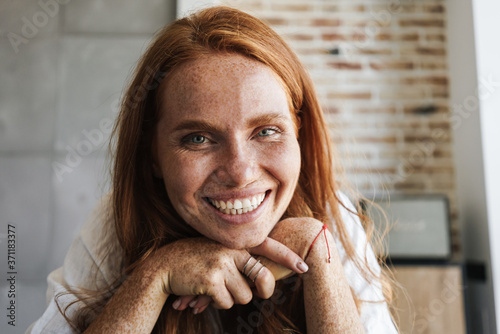 Image of happy ginger woman with freckles smiling and looking at camera