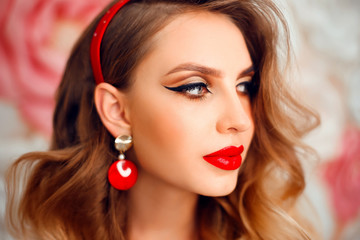 Beauty Portrait of girl with perfect makeup and red jewelry. Beautiful model woman with long curly hairstyle. Eyelashes. Cosmetic eyeshadow. Care and beauty face products.