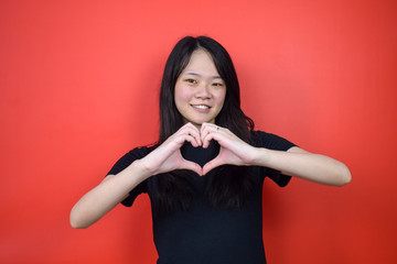 Portrait of Young beautiful asian woman using black T-shirt with red isolated background