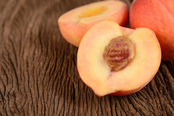 whole and half cut fresh peach with seed on wooden background