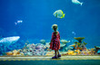 © Irina Schmidt - cute little toddler girl visiting zoo aquarium. Happy baby child watching fishes and jellyfishes, corals. Fascinated child with deep sea wildlife.