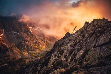 Wall Mural - Trail runner in dramatic sunset mountains landscape. Sport photo, orange edit space..