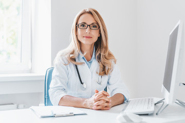 portrait of adult female doctor sitting at desk in office clinic