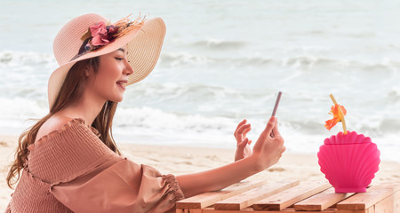 Young Asian traveler woman using mobile phone while travelling on the beach.