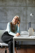 © Bonninstudio/Stocksy - Delighted mature woman answering phone call in office