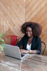 Beautiful black african american business woman are sitting at the table with a laptop, working