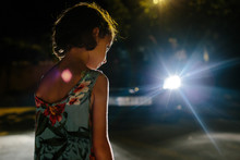 Little Girl Stands In Front Of A Car Light