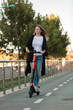 © Javier Pardina/Stocksy - Woman taking a ride with an electric scooter in the city.