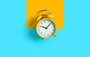 Wall Mural - Orange vintage alarm clock on aqua blue background. Top view. Flat lay