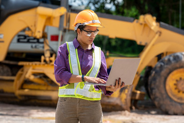 Engineer women use laptop computer on construction site.Real Estate Building Project with construction car vehicle at the work area.