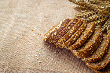 Rye bread isolated. Bakery with crusty loaves and crumbs. Fresh loaf of rustic traditional bread with wheat grain ear or spike plant on natural cotton background. Bio ingredients, healthy with seeds.