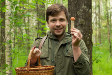 Young Caucasian Man Gathers Mushrooms Showing A Cep From Basket.