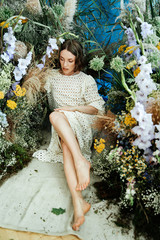 Girl model with beautiful hairstyle and makeup in a white dress with flowers in a fashion-style room for vogue magazine