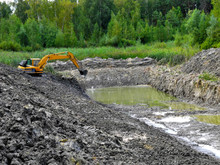 Excavator Digging Pond In Forest. Clay Soil In The Foreground. Lake Construction.