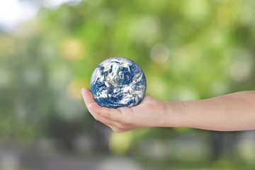 Canvas Print - environment day concept: child hands holding earth over blurred green nature background. elements of