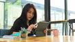 © bongkarn - Female college student preparing her presentation on digital tablet in cafe