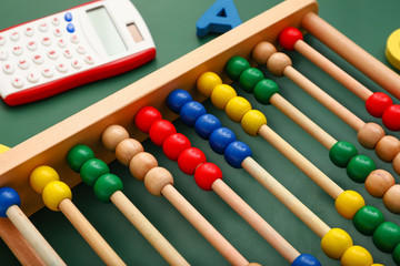 Abacus and calculator on color background