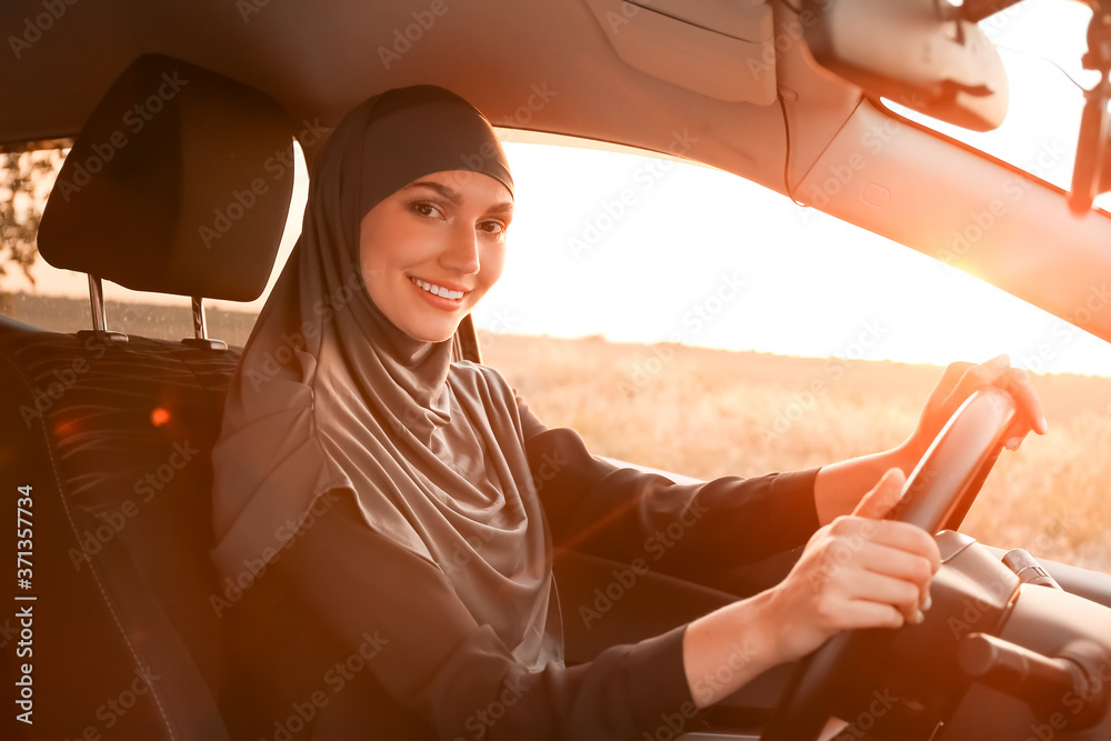 Young Muslim woman sitting in car