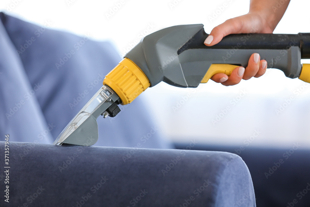 Woman removing dirt from sofa at home