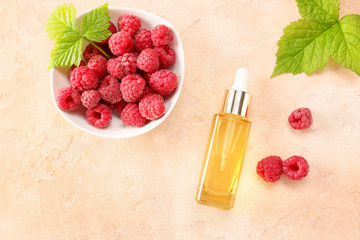 Bottle of raspberry essential oil on color background