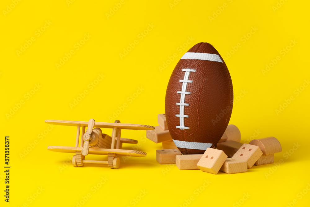 Rugby ball with toys on color background
