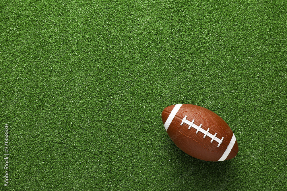 Rugby ball on green grass, top view