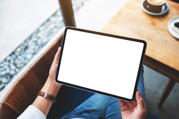 Top view mockup image of a business woman holding black tablet pc with blank white desktop screen in cafe