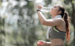 © NAMPIX - Beautiful asian sportswoman drinking water after workout or exercise outdoors, copy space.