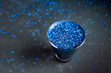 blue shiny stars in a glass on a dark shiny table, top view, holiday cocktail