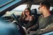 © Romvy - Young Couple on a Road Trip, Man Diving Car with Woman Sitting on Passenger Seat