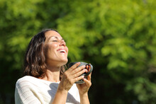 Satisfied Adult Woman Breathing Holding A Coffee Cup Outdoors