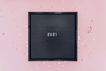 Wall Mural - Numbers 2021 on letterboard on pink background with glitter confetti. New 2021 Year concept.