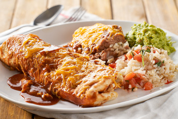 Wall Mural - mexican wet burrtio platter with red enchilada sauce, refried beans, rice and gaucamole