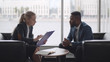 © TommyStockProject - Young HR woman interviews afro-american male candidate for job sitting on couch in conference room