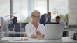 © TommyStockProject - Attractive mature businesswoman sitting at office table working on laptop