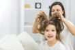 © Andrii - Photo of small girl with long dark messy hair and her mother brushing her hair.