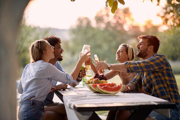 Friends  toasting and drinks  outdoor at sunset.