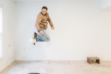 Wall Mural - Young man jumping up in mid-air performing trick with soccer ball playing sports inside dirty basement room in house, empty stains, old carpet