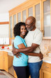 © Tetra Images - Black couple hugging in kitchen