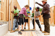 © Tetra Images - Volunteers lifting framed wall at construction site