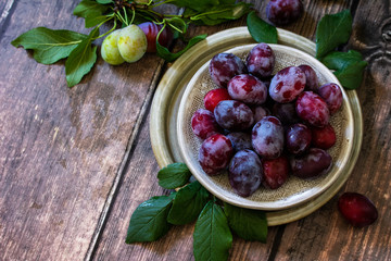 Wall Mural - Ripe juicy plums in a bowl on a wooden background. Copy space.