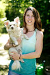 © Westend61 - Smiling young woman carrying cute dog while standing in forest
