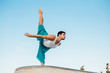 © Westend61 - Young man doing rhythmic gymnastics exercise against clear blue sky